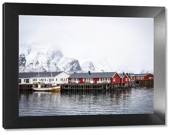 Foggy sky over snowcapped mountains and traditional Rorbu cabins by the sea, Hamnoy, Nordland county, Lofoten Islands, Norway, Scandinavia, Europe