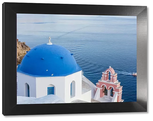 Blue domed white church overlooking boat in Aegean Sea, Santorini, Cyclades, Greek Islands, Greece, Europe
