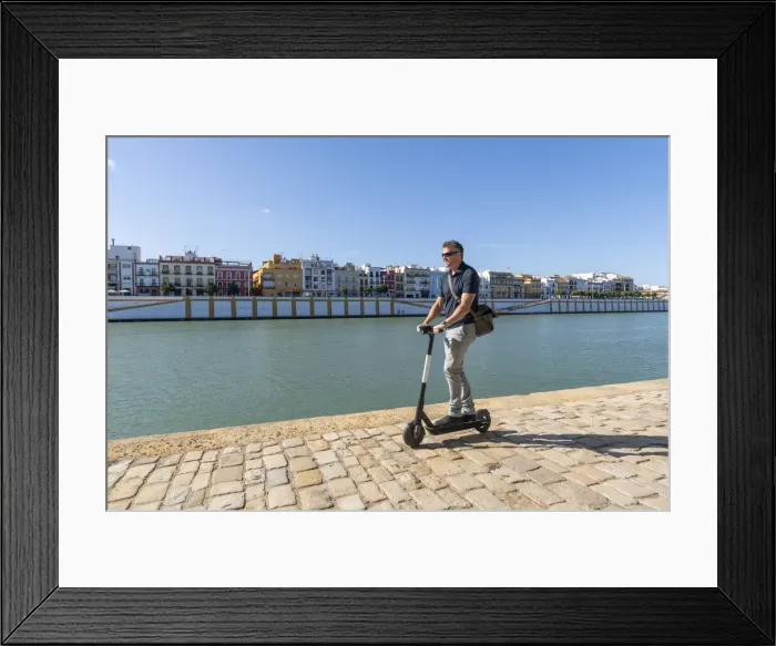 Framed Print : Riding an e-scooter in Seville, Andalusia, Spain, Europe Framed Print : Riding an e-scooter in Seville, Andalusia, Spain, Europe