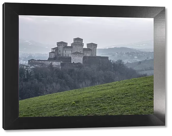 Medieval castle of Torrechiara with square towers on a hill on a foggy day, Torrechiara, Emilia Romagna, Italy, Europe