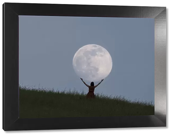 Full moon portrait at blue hour with a girl holding the moon above her head, Emilia Romagna, Italy, Europe