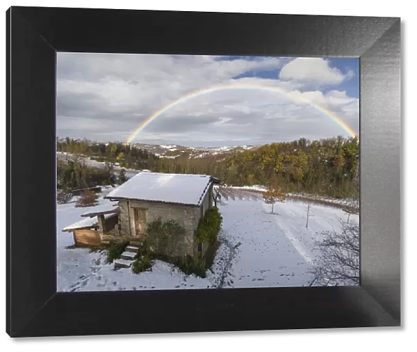 Rainbow arch above a small cottage and a snowy winter countryside landscape, Emilia Romagna, Italy, Europe