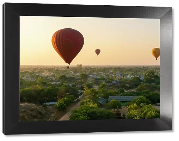 Hot-air balloons at sunrise over village near Bagan (Pagan), Myanmar (Burma), Asia