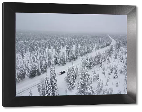 View from above of a car travelling icy road in the middle of the frozen forest covered with snow, Akaslompolo, Kolari, Pallas-Yllastunturi National Park, Lapland region, Finland, Europe