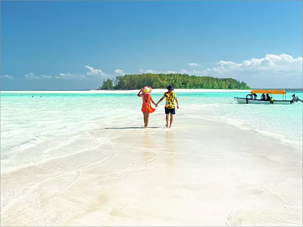 Man and woman in love holding hands walking on empty sandy shore surrounded by the Indian Ocean, Zanzibar, Tanzania, East Africa, Africa