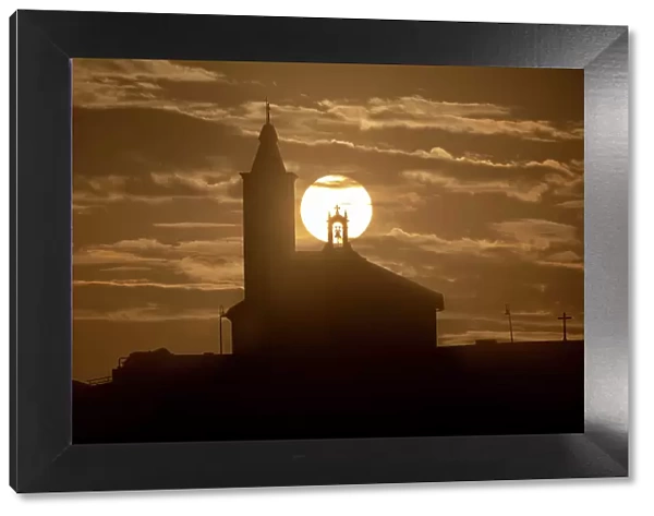 Sun aligned with the silhouette of the church of Luarca, Asturias, Spain, Europe