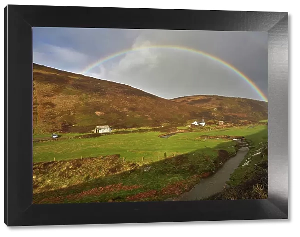 A valley rainbow forms in the face of an autumn squall, in Duckpool, a remote cove near Bude, north coast of Cornwall, England, United Kingdom, Europe