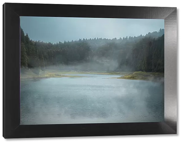 Lagoa do Eguas lake framed by a forest in a cloudy day with some low fog, Azores islands, Sao Miguel island, Portugal, Atlantic, Europe
