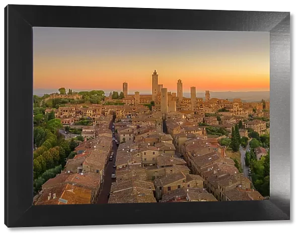 Elevated view of rooftops and town at sunrise, San Gimignano, Tuscany, Italy, Europe