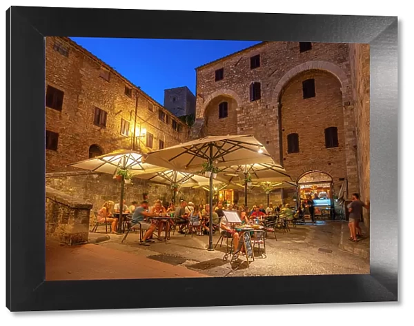 View of restaurant in historic centre at dusk, San Gimignano, UNESCO World Heritage Site, Province of Siena, Tuscany, Italy, Europe