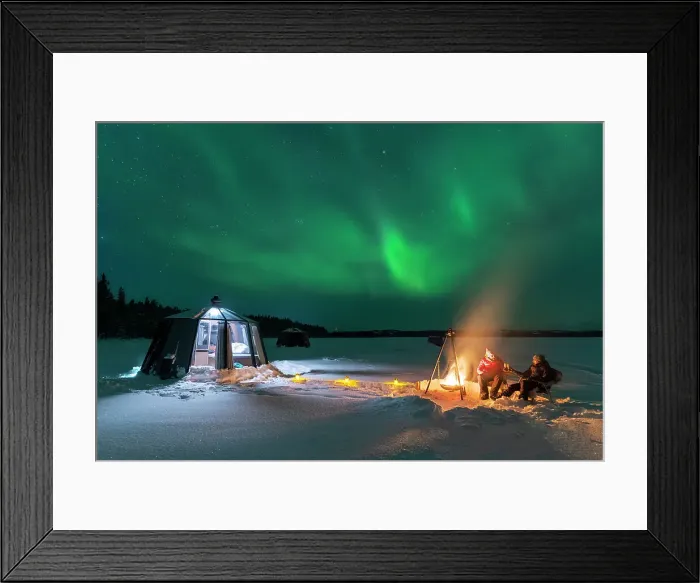 Framed Print : Night view of two people enjoyng dinner outside around a campfire close to the illuminated glass igloo with Northern Lights (Aurora Borealis) dancing in the sky, Jokkmokk, Norrbotten, Swedish Lapland, Sweden, Scandinavia, Europe