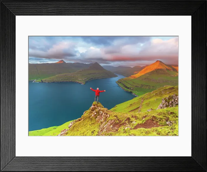 Framed Print : Happy hiker stands on top of the cliff overlooking the fjord of Funningur, Eysturoy island, Faroe islands, Denmark, Europe Framed Print : Happy hiker stands on top of the cliff overlooking the fjord of Funningur, Eysturoy island, Faroe islands, Denmark, Europe