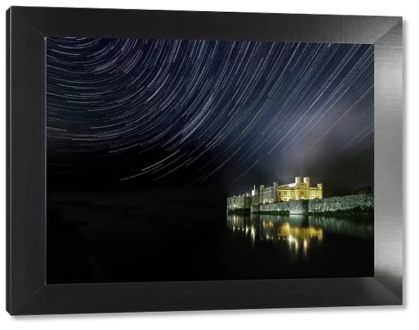 Leeds castle illuminated reflected in moat showing star trails in the night sky, near Maidstone, Kent, England, United Kingdom, Europe