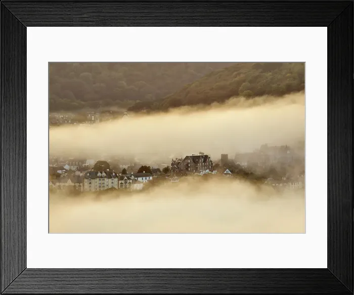 Framed Print : Sea fog envelops the coastal town of Lynton, lit by the light of sunset, seen from Countisbury Hill, Exmoor National Park, Devon, England, United Kingdom, Europe Framed Print : Sea fog envelops the coastal town of Lynton, lit by the light of sunset, seen from Countisbury Hill, Exmoor National Park, Devon, England, United Kingdom, Europe