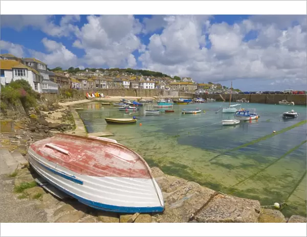 Small unturned boat on the quay and small boats in the enclosed harbour at Mousehole