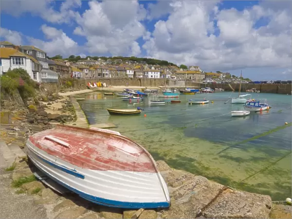 Small unturned boat on the quay and small boats in the enclosed harbour at Mousehole