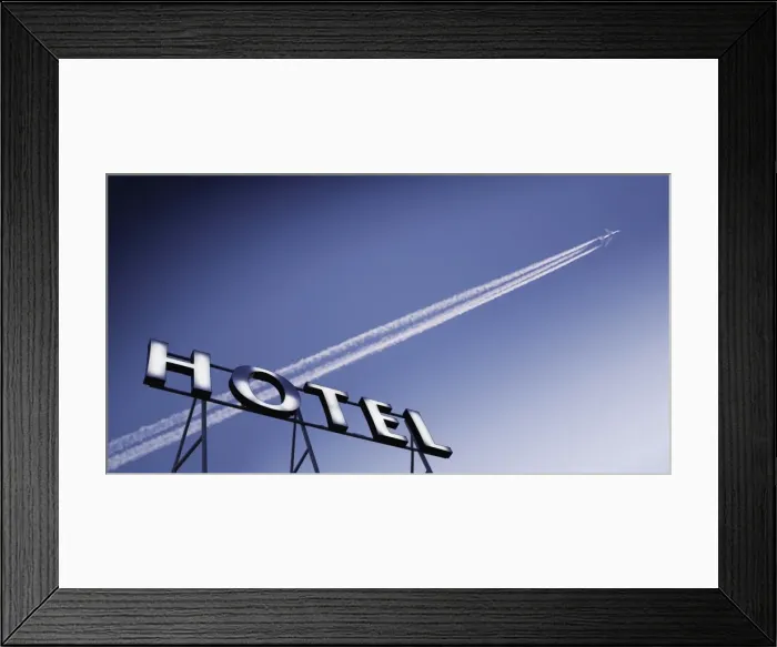 Framed Print : Plane in blue sky with vapour trail and hotel sign Framed Print : Plane in blue sky with vapour trail and hotel sign