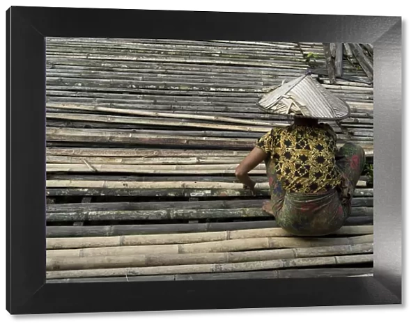 Iban tribeswoman mending bamboo longhouse verandah floor, Lemanak River