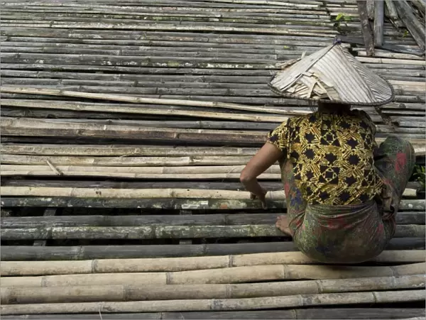 Iban tribeswoman mending bamboo longhouse verandah floor, Lemanak River