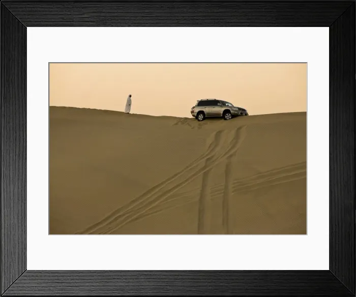 Framed Print : Man in traditional Arab dress looking at 4x4 car stuck on the ridge of a dune during a desert safari near Abu Dhabi, United Arab Emirates Framed Print : Man in traditional Arab dress looking at 4x4 car stuck on the ridge of a dune during a desert safari near Abu Dhabi, United Arab Emirates