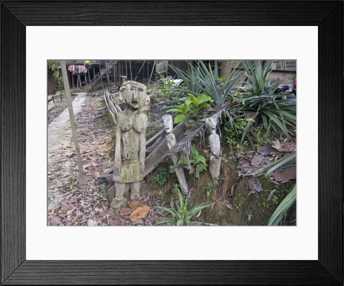 Framed Print : Carved spirits of men and a woman standing at the entrance to Iban tribal longhouse at Ngemah beach on the Lemanak River, Sarawak, Malaysian Borneo, Malaysia, Southeast