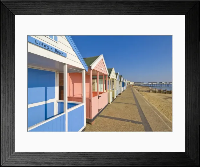 Framed Print : Brightly painted beach huts in the afternoon sunshine, on the seafront promenade Framed Print : Brightly painted beach huts in the afternoon sunshine, on the seafront promenade