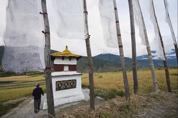 A man circumambulating a stupa with prayer flags, Punakha, Bhutan, Asia