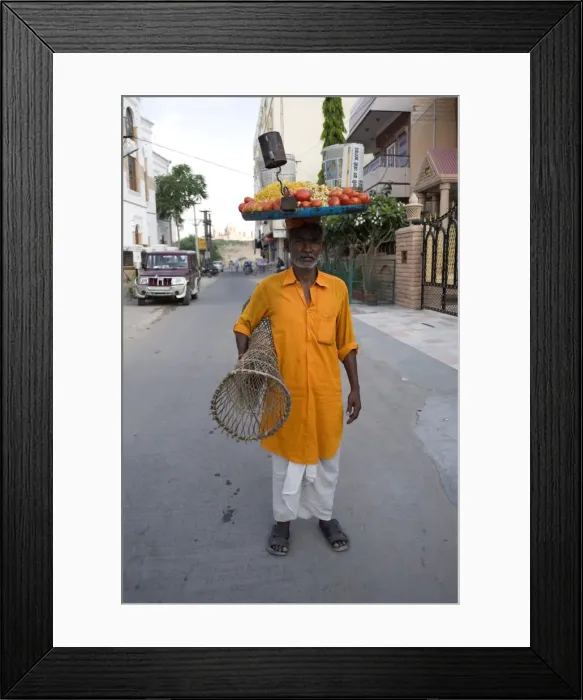 Framed Print : Man in yellow kurta with tray of snacks on his head and table under his arm