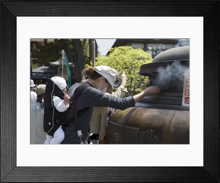 Framed Print : Mother with baby using incense smoke to cure bodily ailments at Zenkoji Temple
