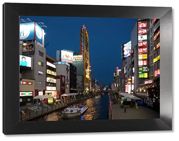 Tour boat on Dotonbori River glides past shops and restaurants in Namba