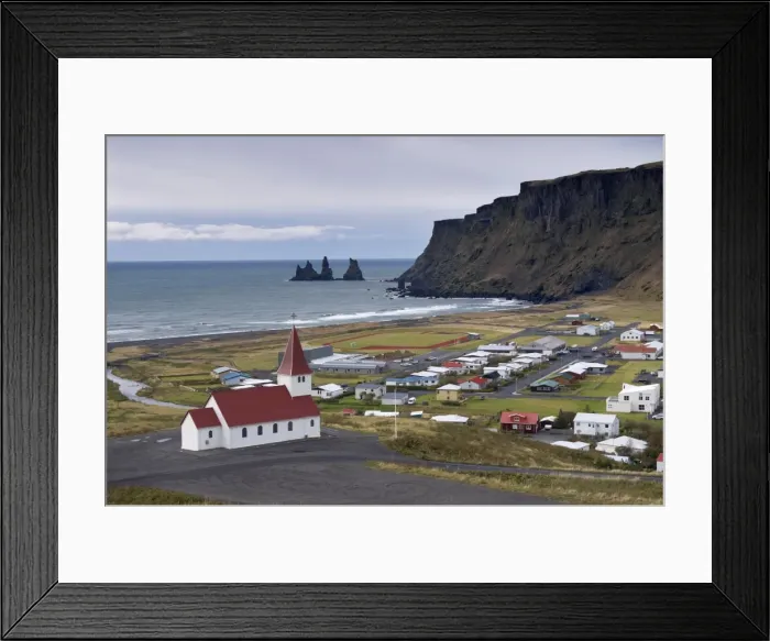 Framed Print : Church, village of Vik (Vik a Myrdal) and Reynisdrangar sea stacks in the distance