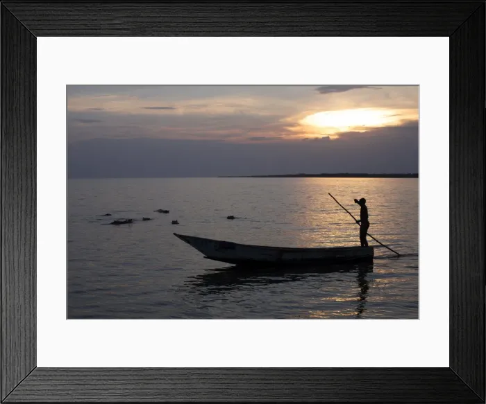 Framed Print : A man navigates his dugout canoe past bathing hippos in Lake Edward, Queen Elizabeth National Park Framed Print : A man navigates his dugout canoe past bathing hippos in Lake Edward, Queen Elizabeth National Park
