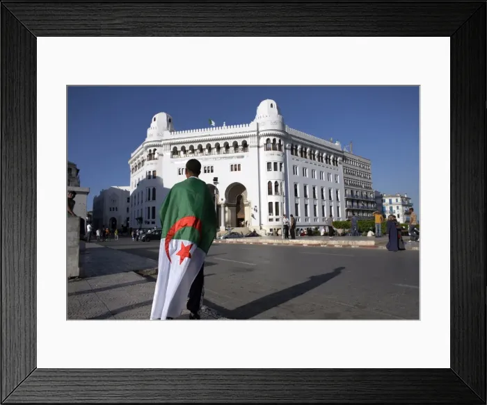 Framed Print : A man with an Algerian flag stands in front of Grande Poste in Algiers Framed Print : A man with an Algerian flag stands in front of Grande Poste in Algiers