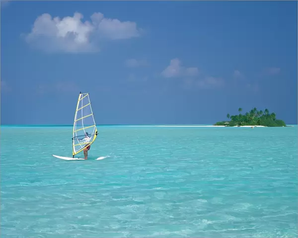 Young man windsurfing near tropical island and lagoon in the Maldives, Indian Ocean