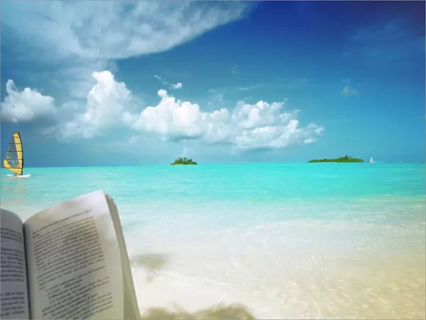 Reading book on the beach, windsurfing and islands in the distance, the Maldives