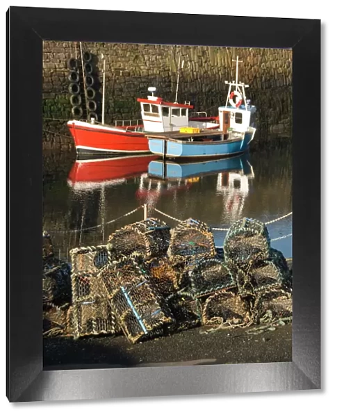 Lobster creels in the foreground with fishing boats in the harbour, Crail