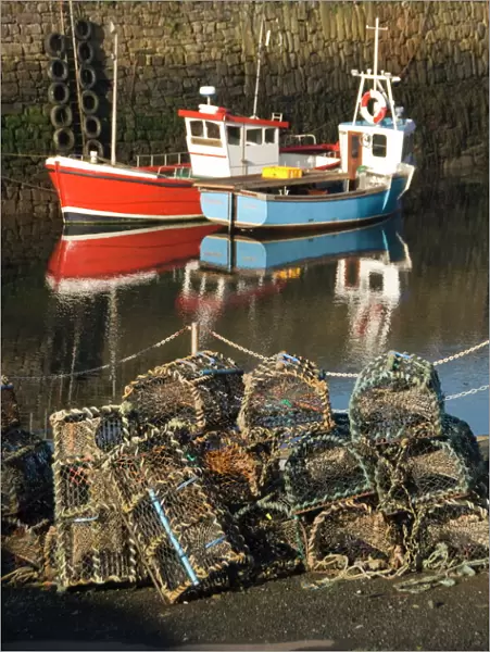 Lobster creels in the foreground with fishing boats in the harbour, Crail