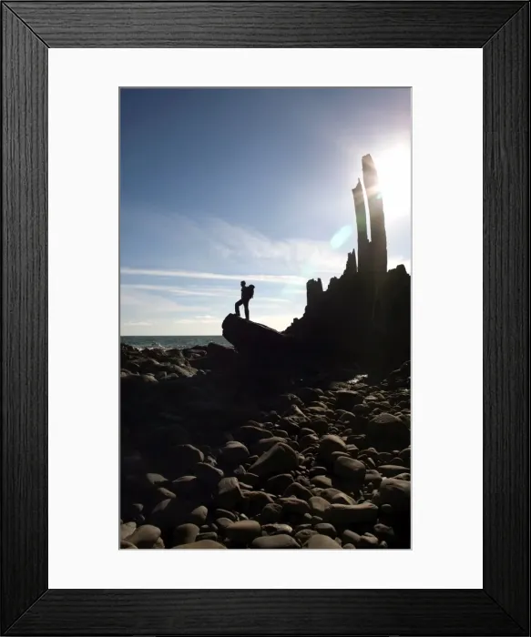 Framed Print : A walker stands on a boulder beside the isolated Bear Rock, a Culm pinnacle near Hartland Quay