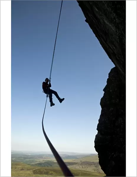 A climber abseiling from a cliff in the Ogwen Valley, Snowdonia, North Wales