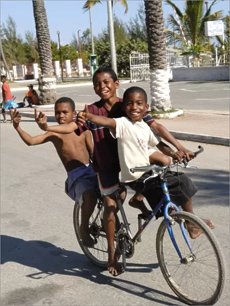 Happy boys cycling through the streets of Toliara, Madagascar, Africa