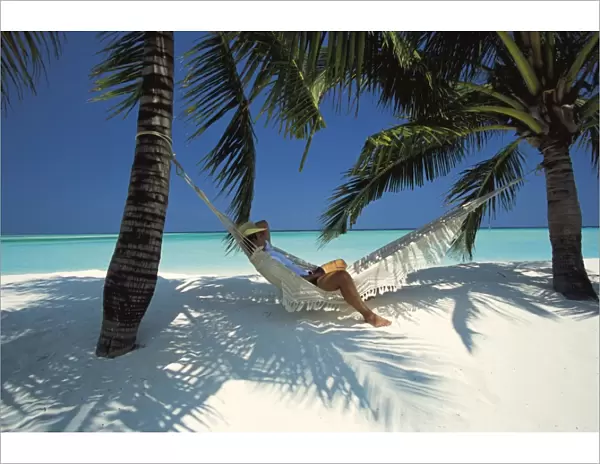 Man relaxing on a beachside hammock, Maldives, Indian Ocean, Asia