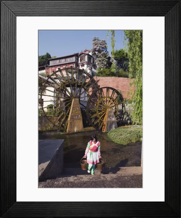 Framed Print : A Bai girl carrying buckets of water in front of a water wheel in Lijiang Old Town Framed Print : A Bai girl carrying buckets of water in front of a water wheel in Lijiang Old Town