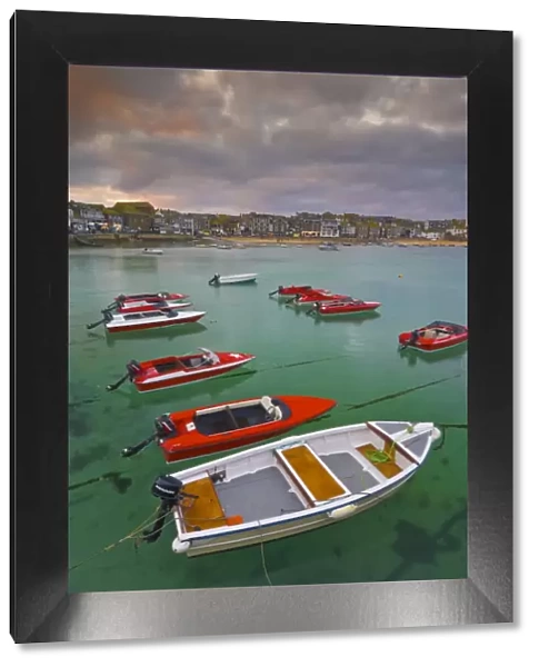 Strange cloud formation in a stormy sky at sunset, with small red speedboats for hire with an incoming tide in the harbour at St. Ives, Cornwall, England, United