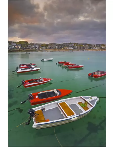 Strange cloud formation in a stormy sky at sunset, with small red speedboats for hire with an incoming tide in the harbour at St. Ives, Cornwall, England, United