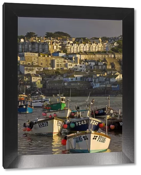 A stormy sky at sunset with small Cornish fishing boats in the harbour at St