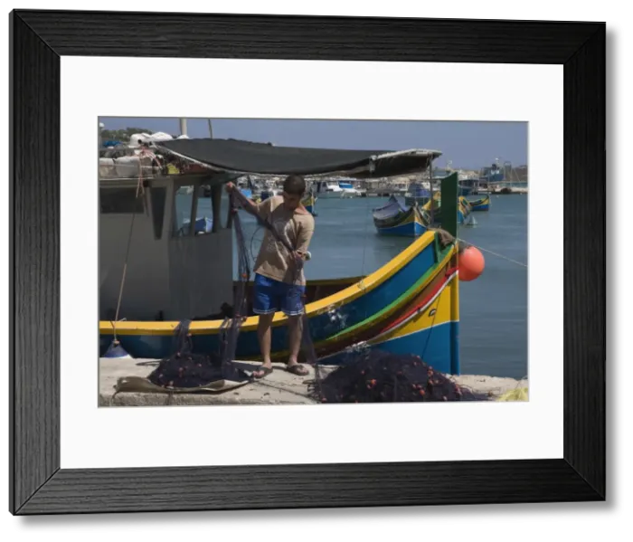 Framed Print : Sorting out the fishing net with brightly coloured fishing boats called Luzzus at Marsaxlokk Framed Print : Sorting out the fishing net with brightly coloured fishing boats called Luzzus at Marsaxlokk