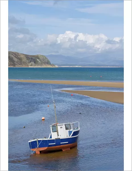 Lone fishing boat waiting for the incoming tide on the Warren, Abersoch beach, St