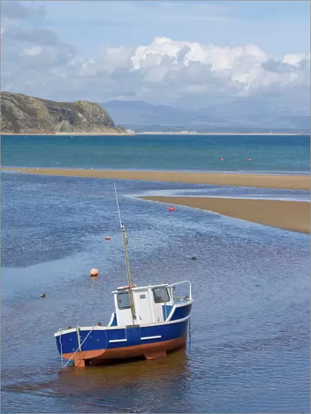 Lone fishing boat waiting for the incoming tide on the Warren, Abersoch beach, St