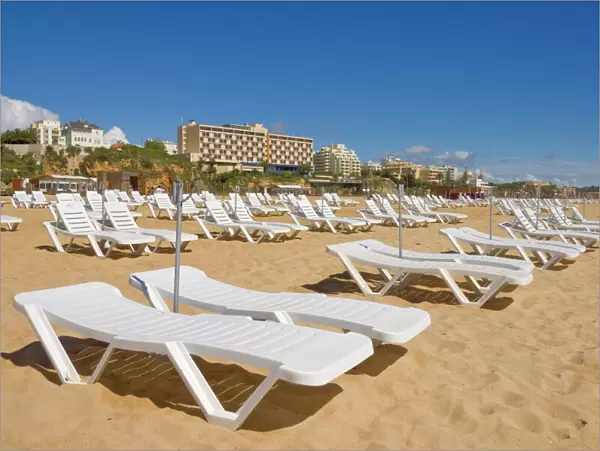 Empty white sun lounger sunbeds on Praia da Rocha beach, Portimao, Algarve