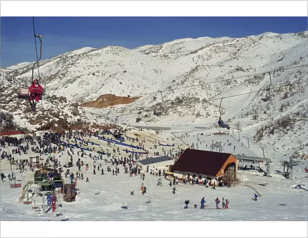 Woman on chairlift above crowds of skiers and tourists at the Neve Ativ Ski Resort on Mount Hermon